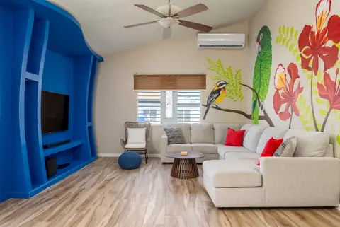 Living room with parrot and flamboyán mural — Casa Paraíso vacation rental in Isabela, Puerto Rico